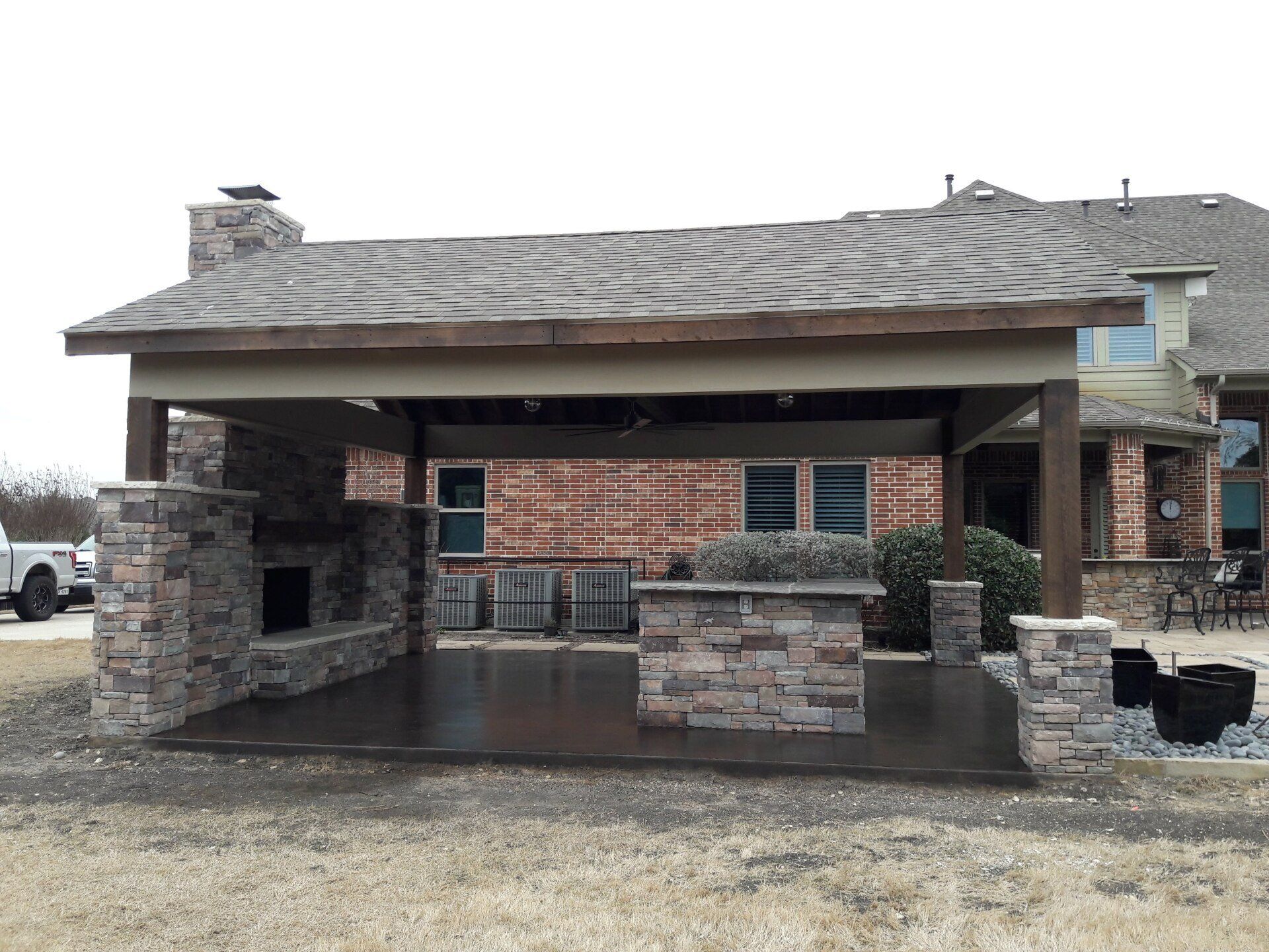 A brick house with a covered patio area and a fireplace.