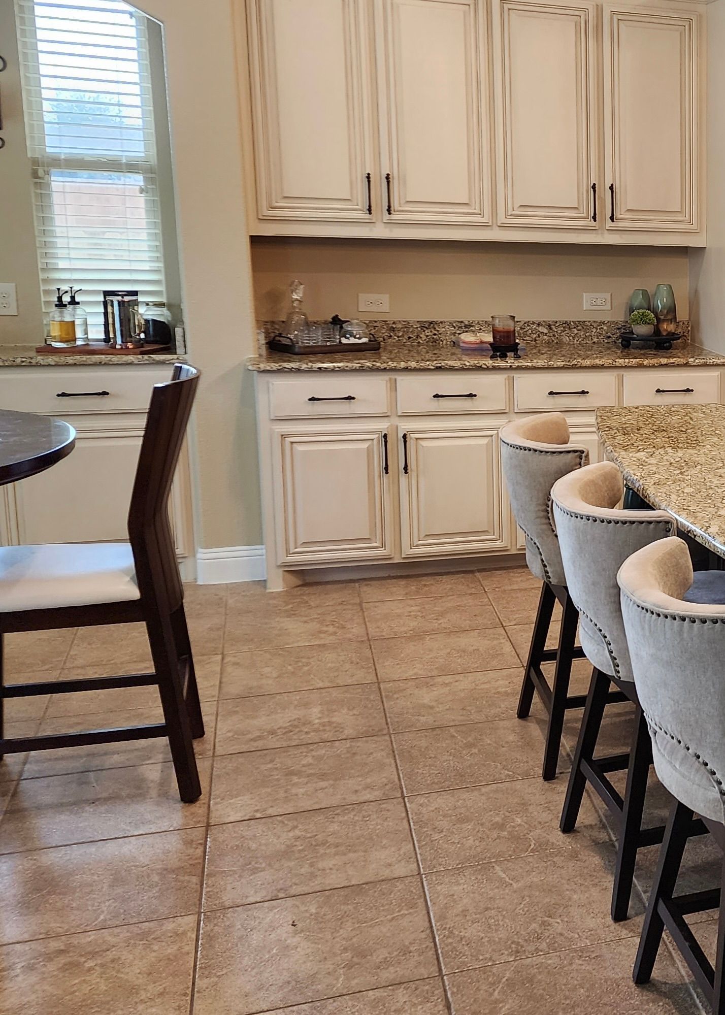 Kitchen with cream cabinets, granite countertops, and bar stools.