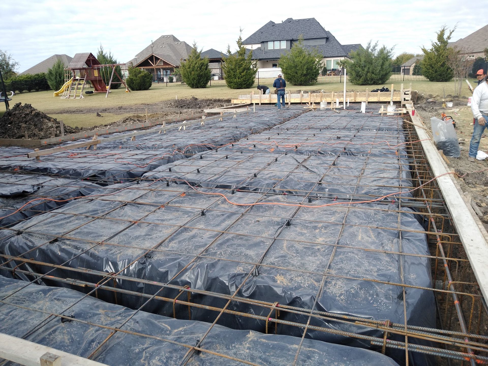 A construction site with a large house in the background.