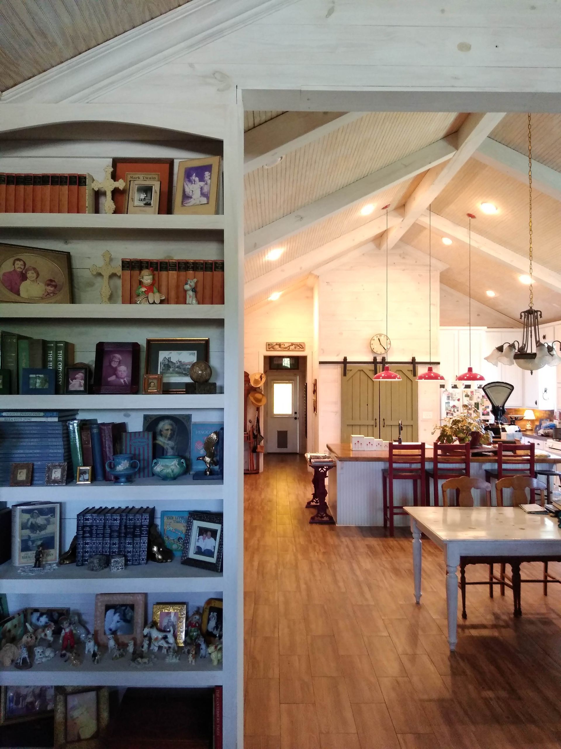 A room with a table and chairs and a bookshelf with pictures on it