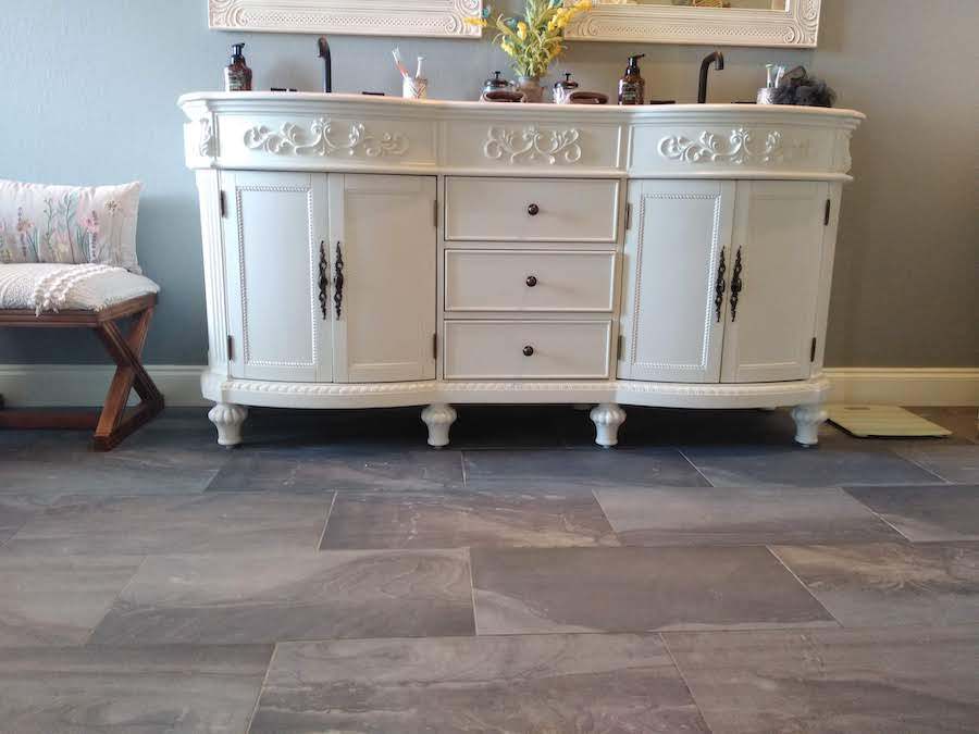 A bathroom with a white vanity , sink and mirror.
