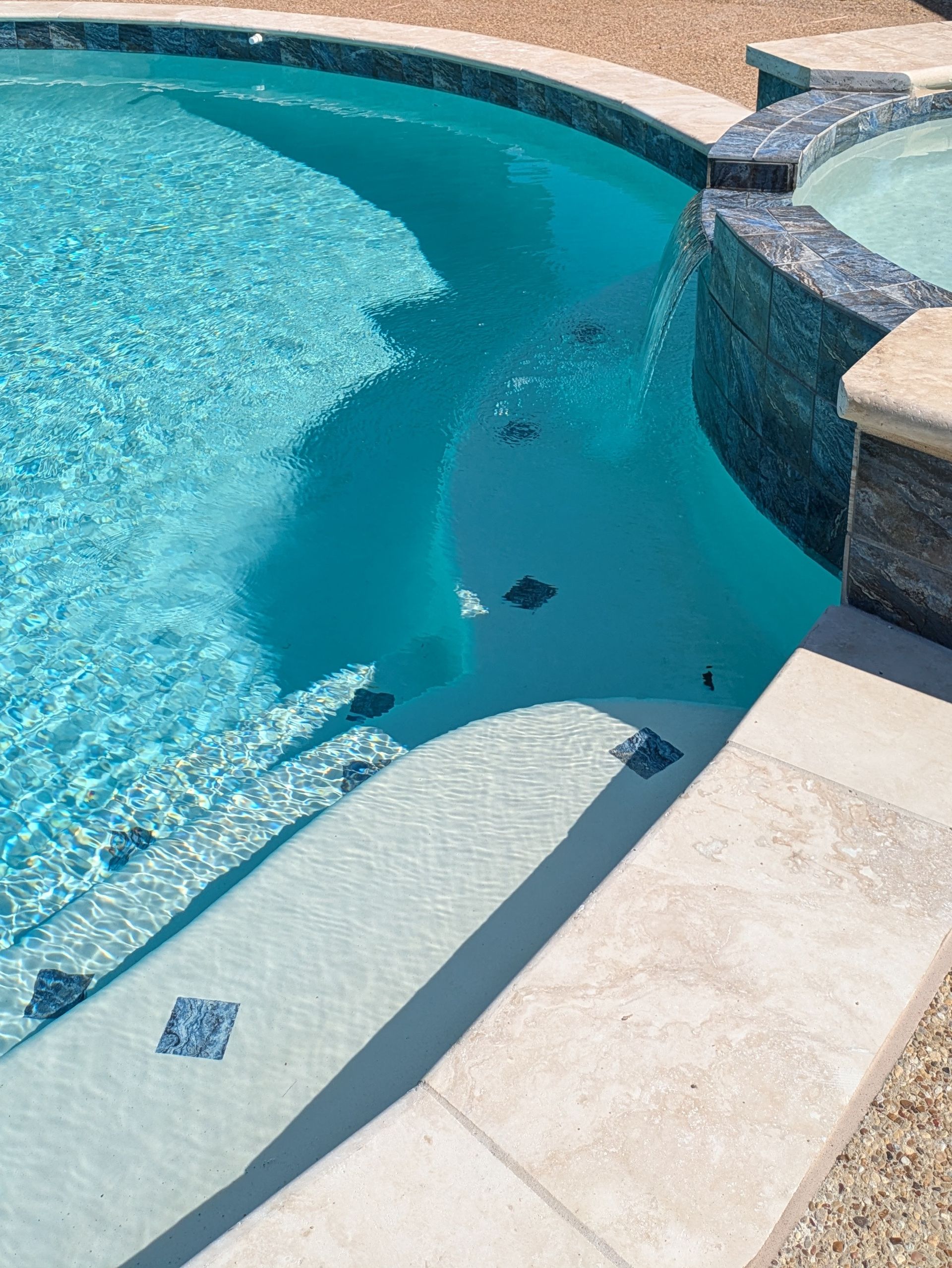 A swimming pool with a hot tub next to it.