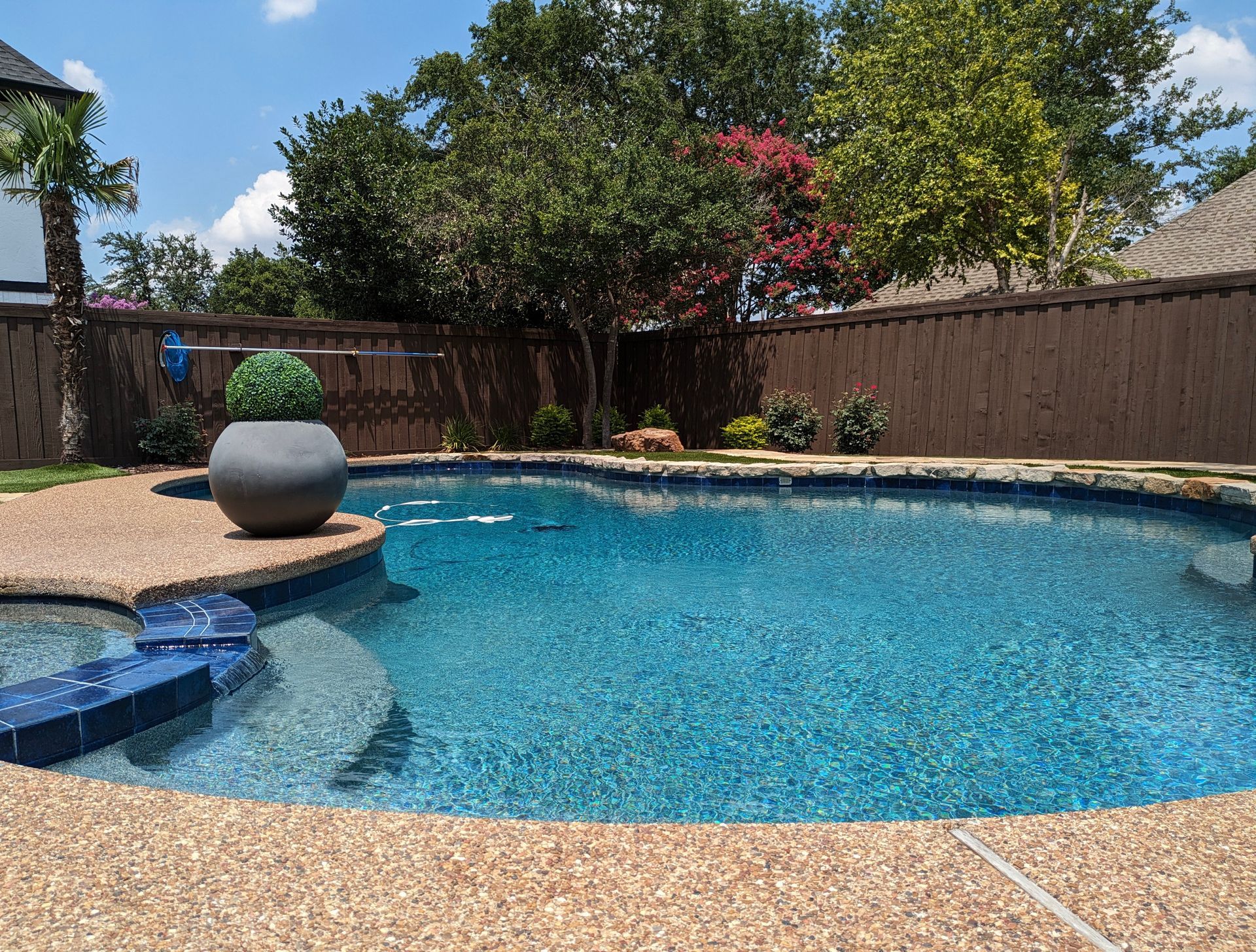There is a large swimming pool in the backyard of a house.