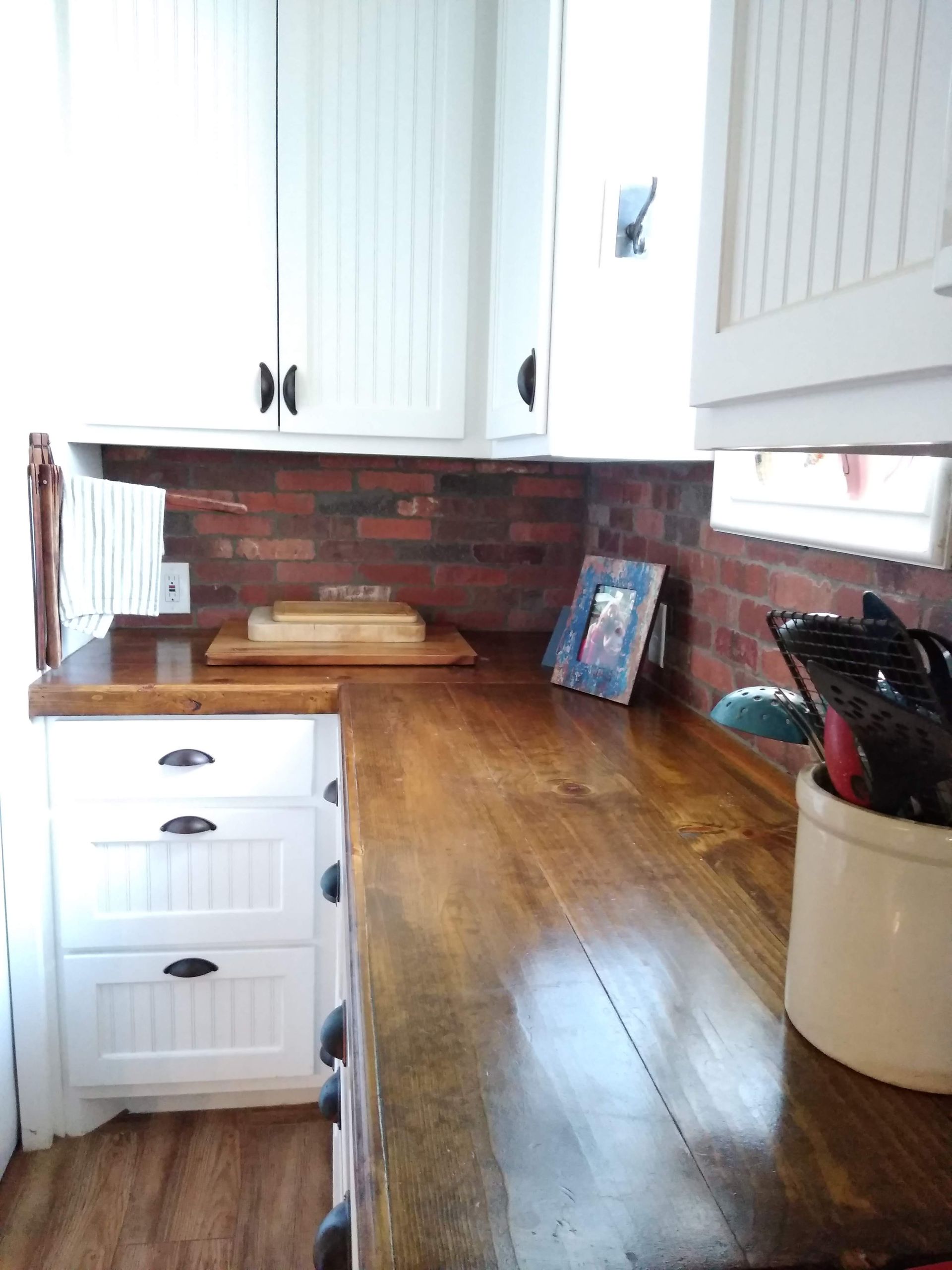 A kitchen with a wooden counter top and white cabinets