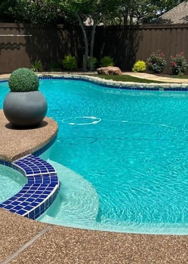 Swimming pool with blue water, steps, and decorative pot.