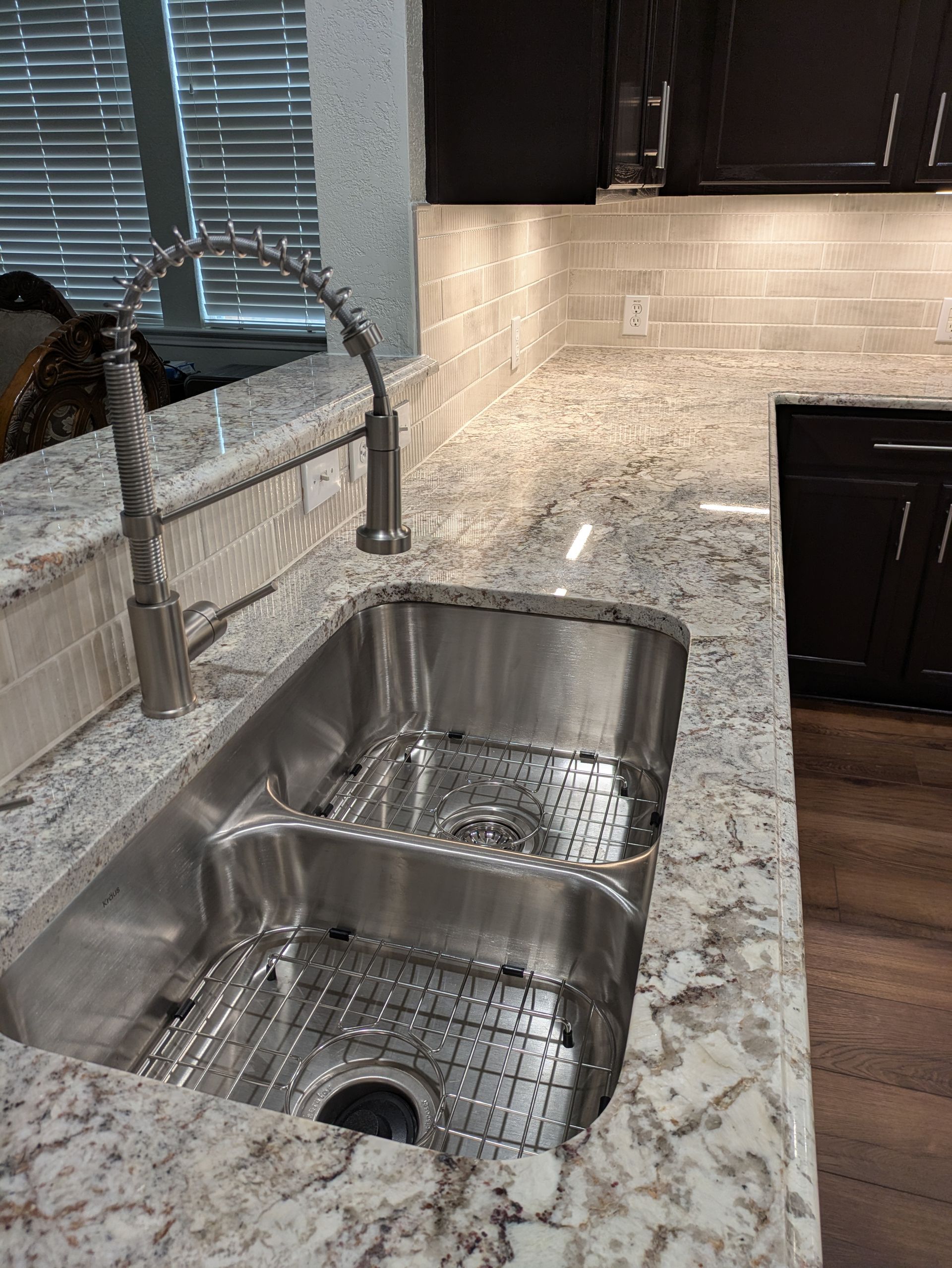 Stainless steel kitchen sink with a faucet on a granite countertop.