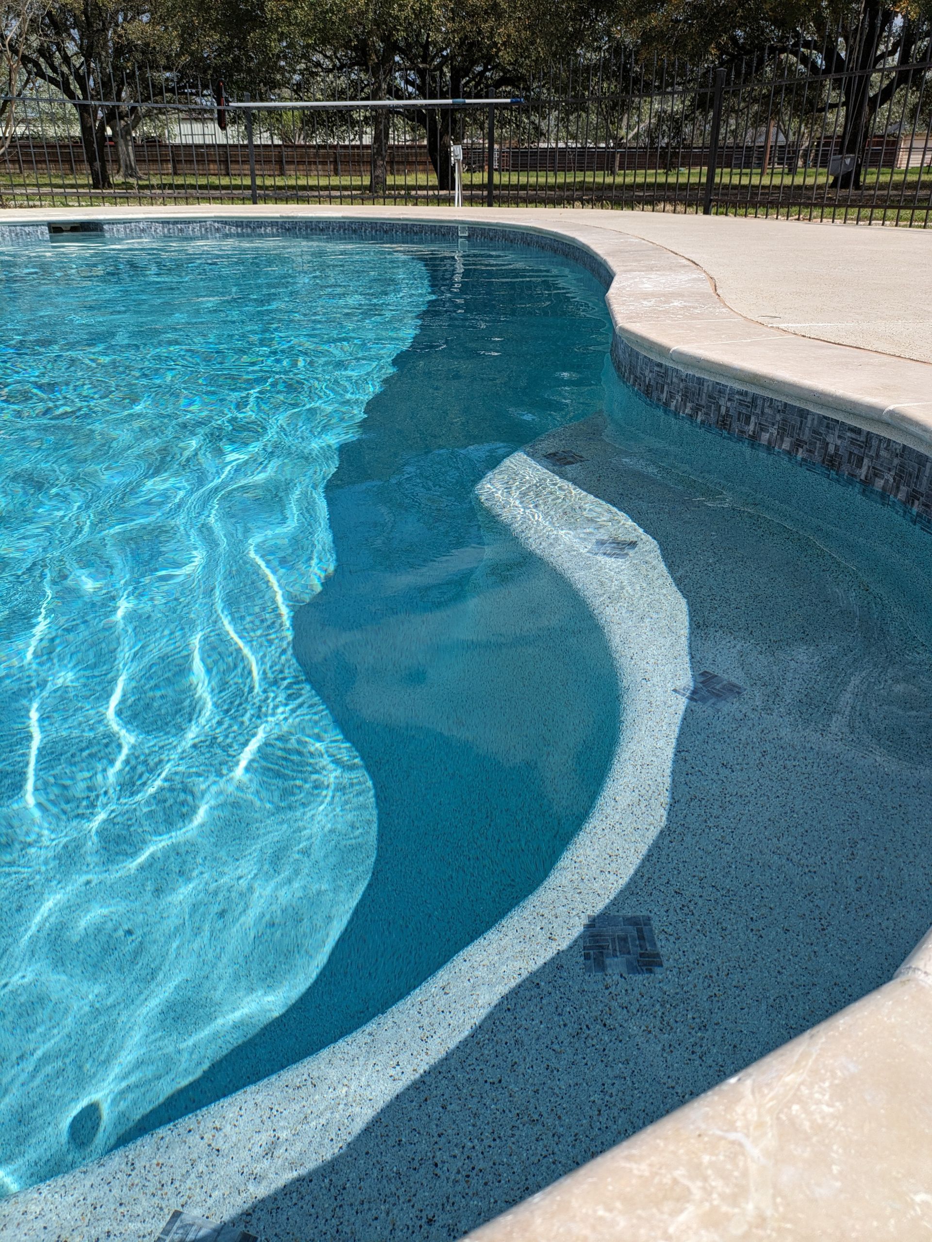 A close up of a swimming pool with trees in the background.
