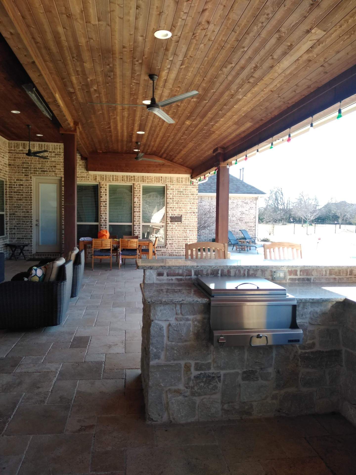 A patio with a wooden ceiling and a stainless steel grill