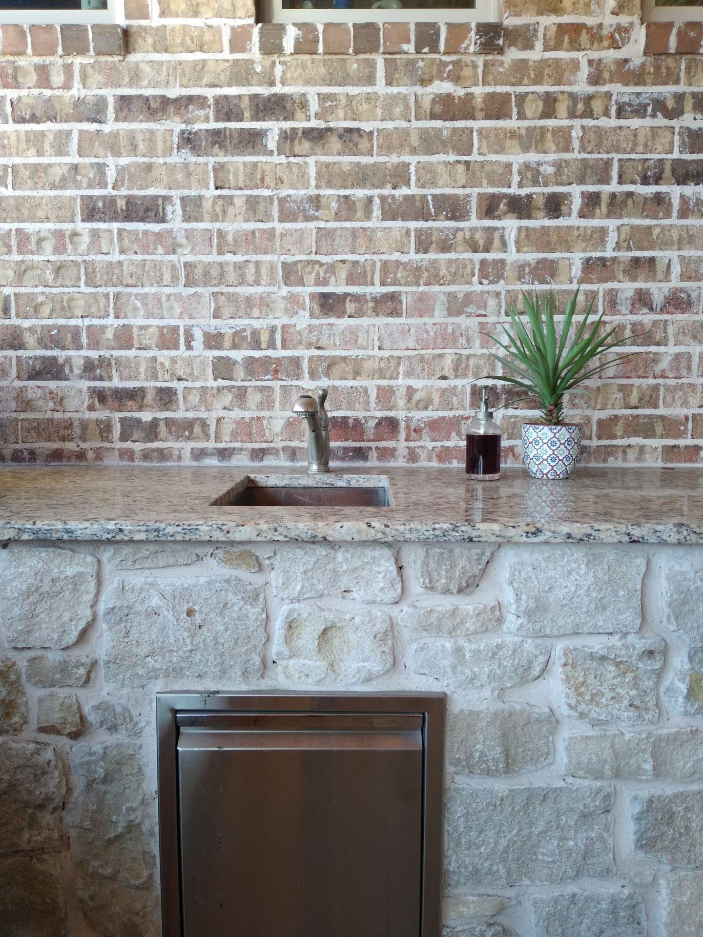 A kitchen with a sink and a brick wall.