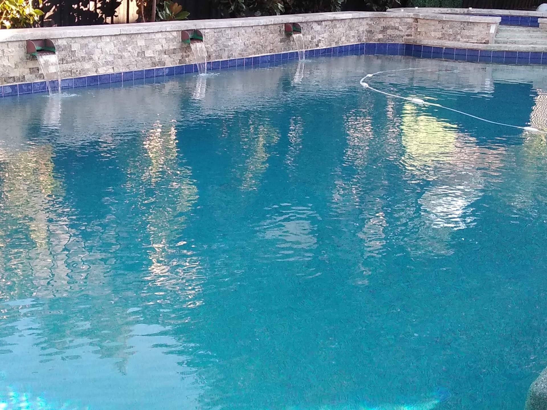 A large swimming pool with a stone wall surrounding it