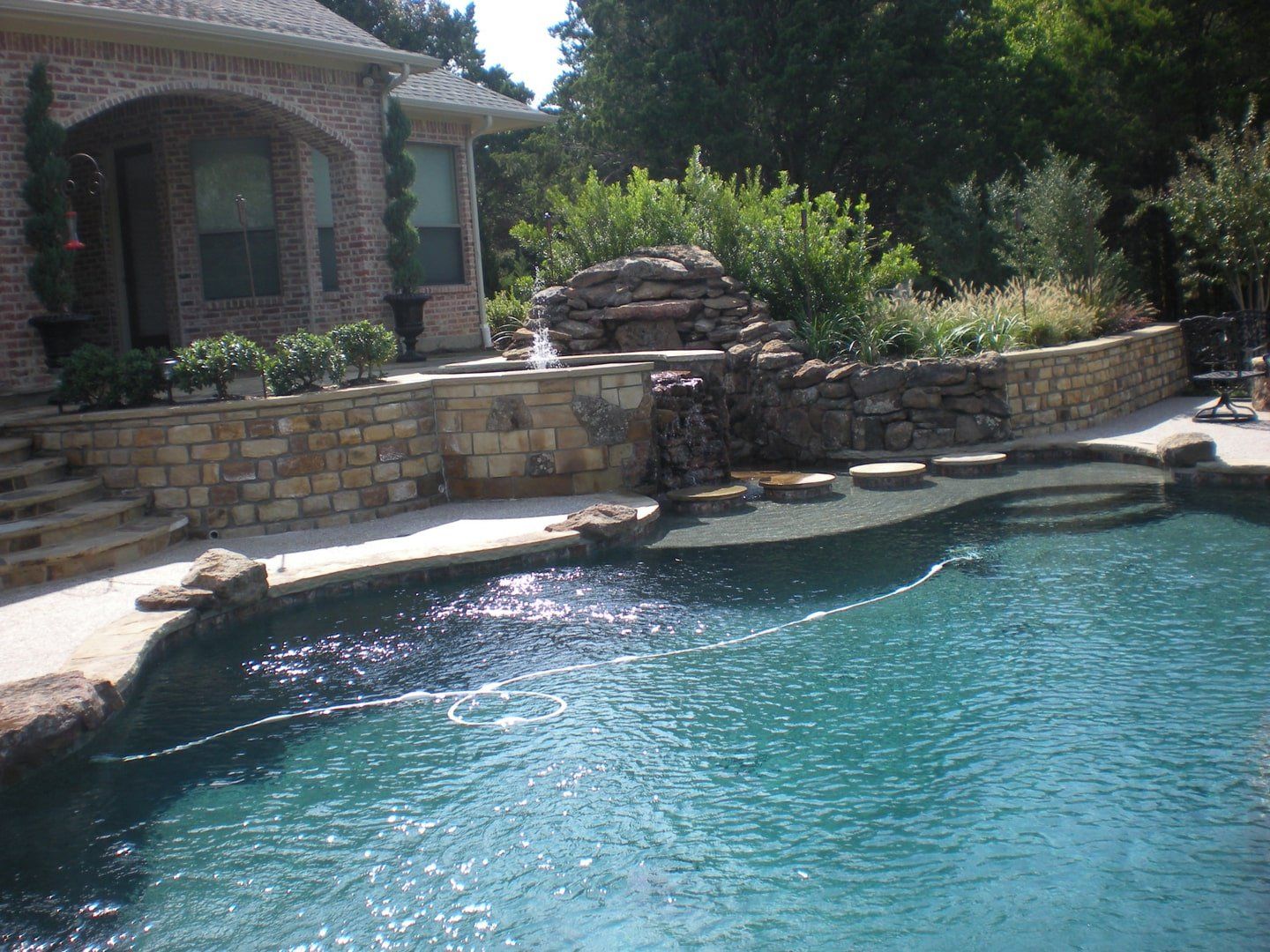 A large swimming pool in front of a brick house
