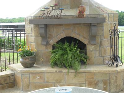 A stone fireplace with a potted plant in front of it.