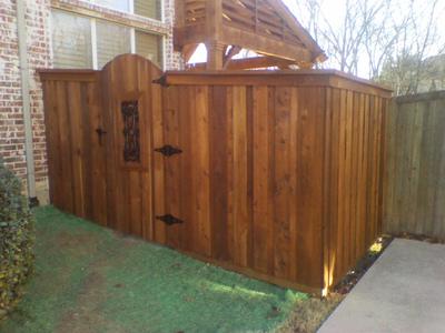 A wooden fence with a gate in the backyard of a house.