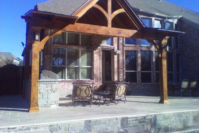 A large brick house with a wooden pergola over a patio.