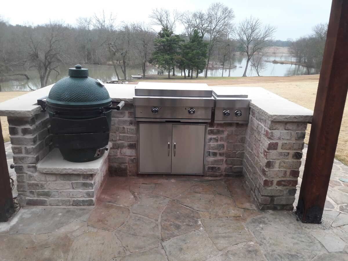 A large green egg is sitting on top of a brick grill.