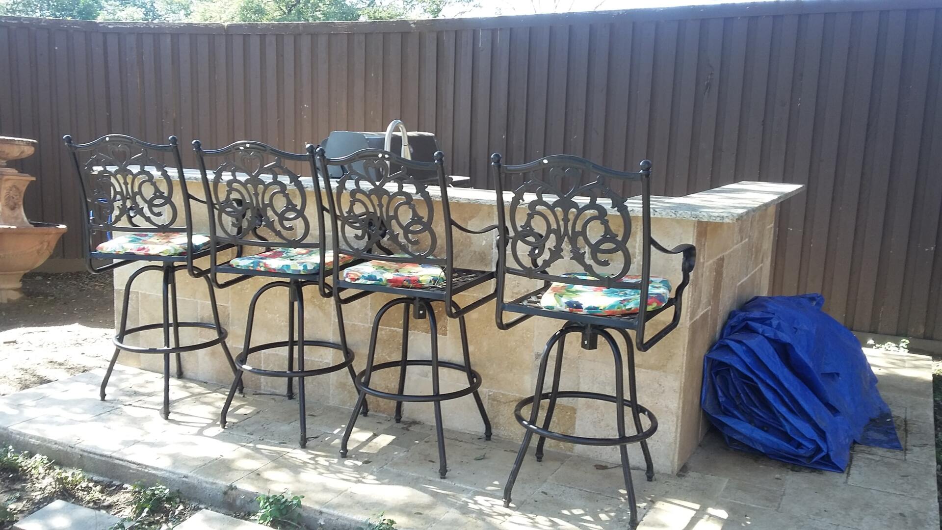 A row of bar stools are sitting in front of a wooden fence.