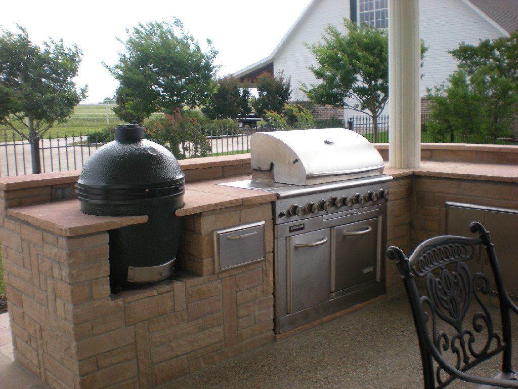 An outdoor kitchen with a grill and a big green egg