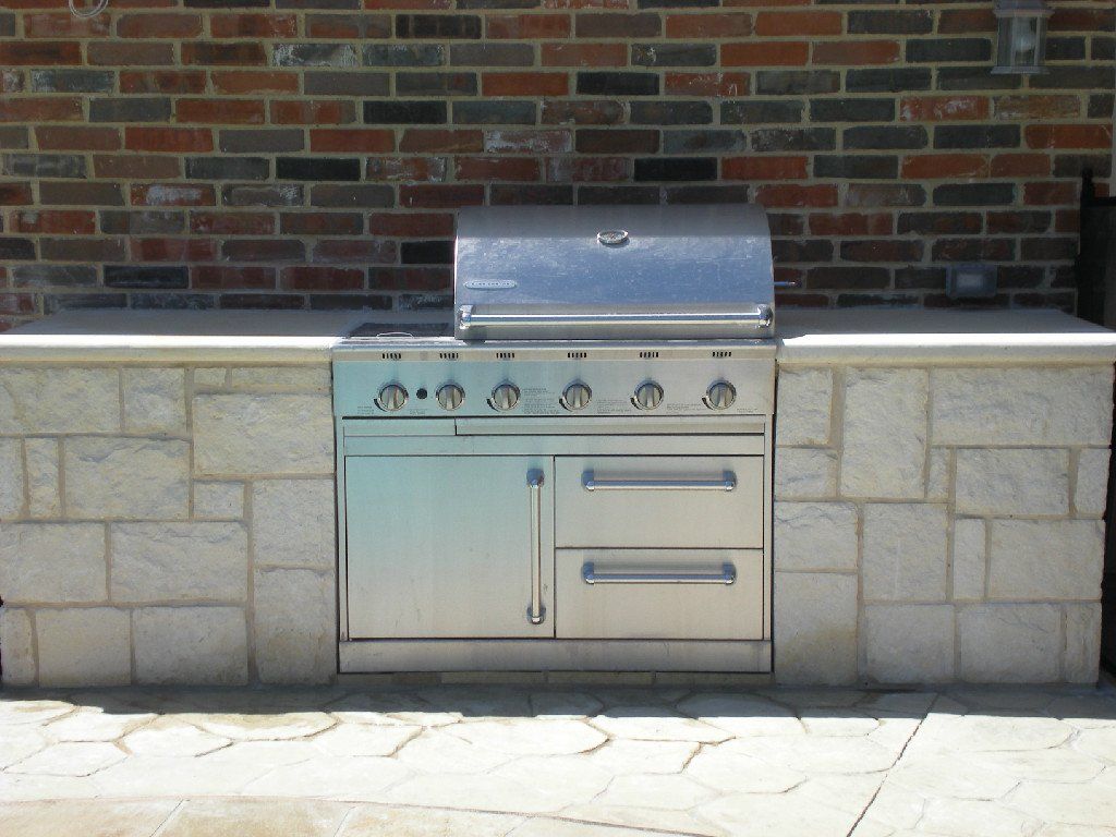 A stainless steel grill is built into a brick wall