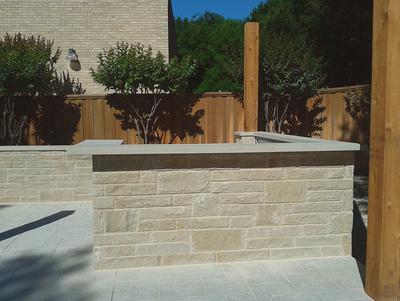 A brick wall with a wooden fence in the background