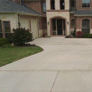 A large brick house with a concrete driveway in front of it.