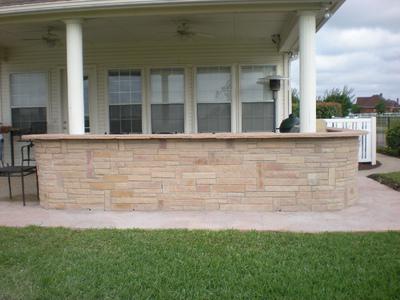 A brick wall is sitting in front of a house.