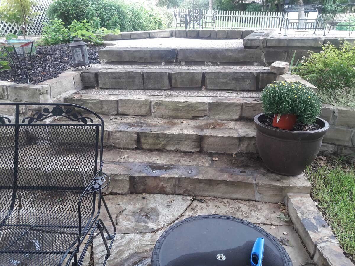 A patio with stairs , chairs and a fire pit
