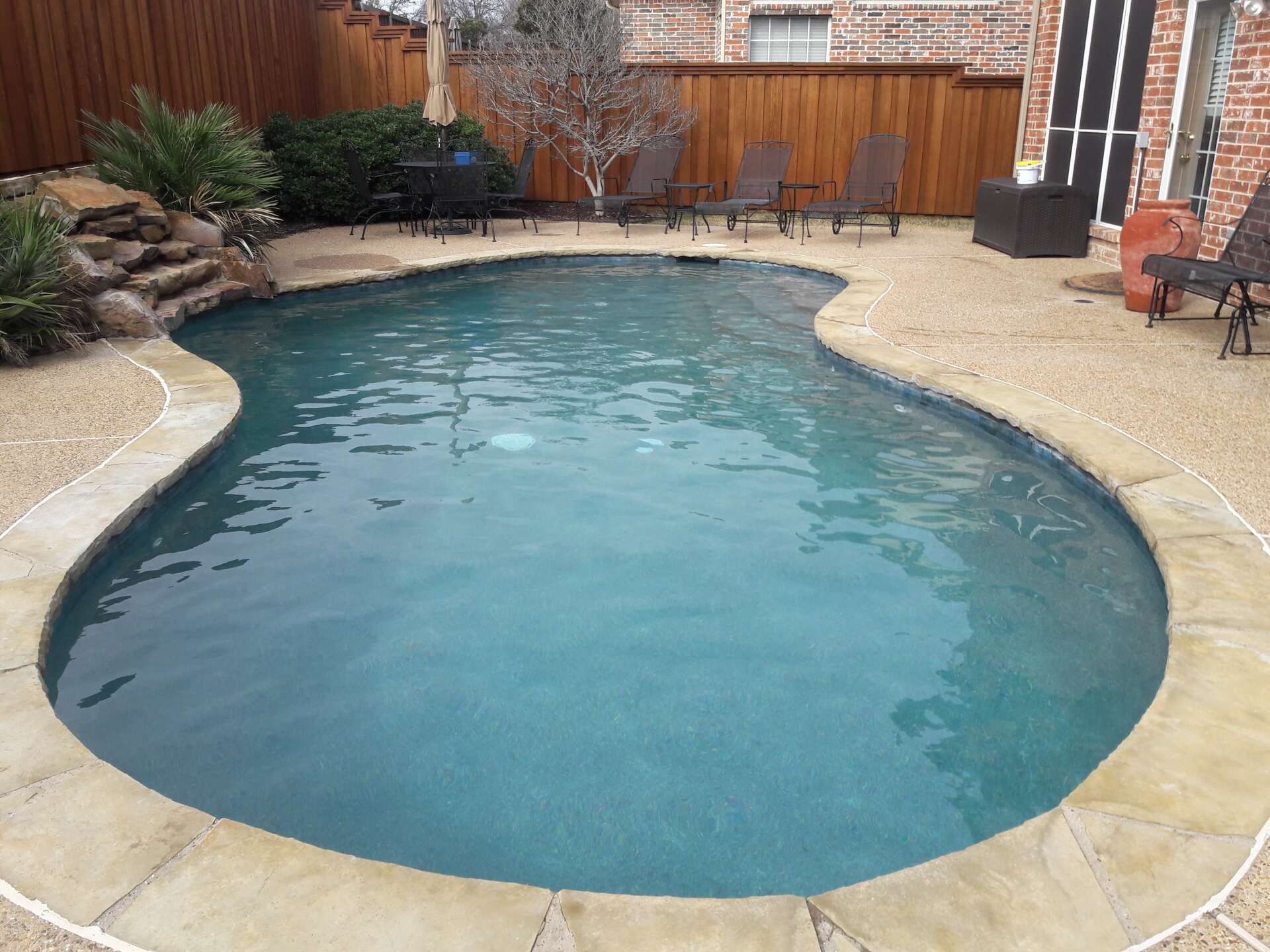 A large swimming pool surrounded by chairs and a fence
