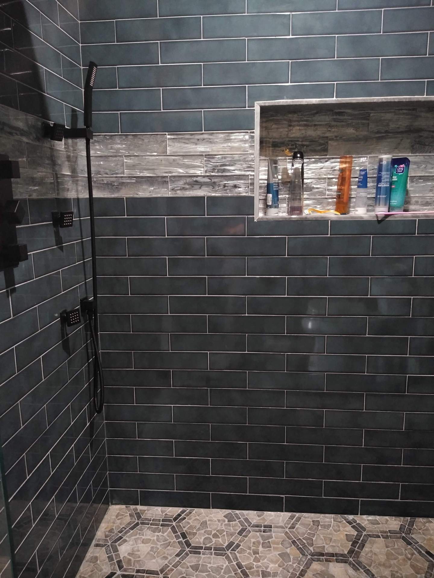 A bathroom with a walk in shower and a built in shelf.