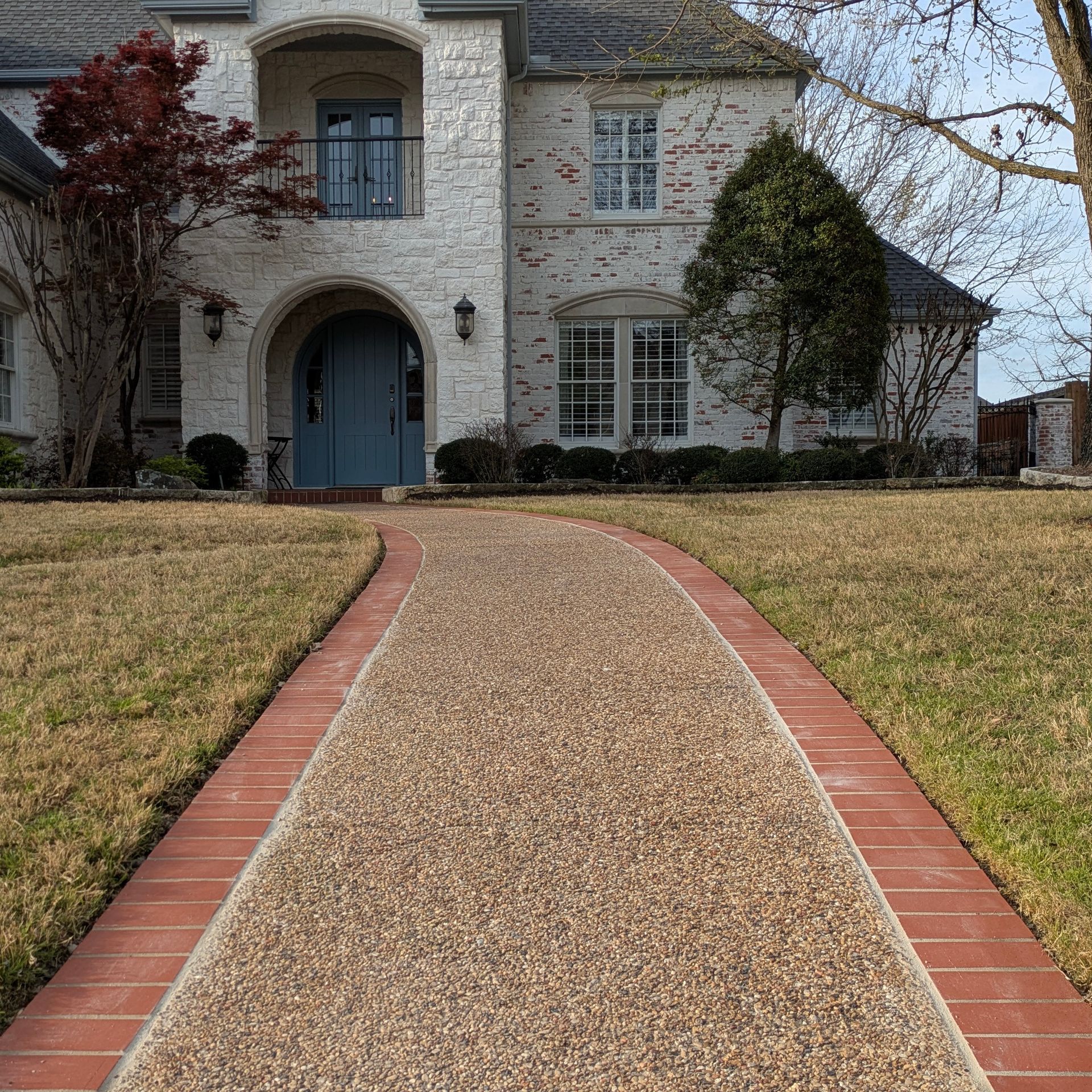 A brick walkway leading to a large white house