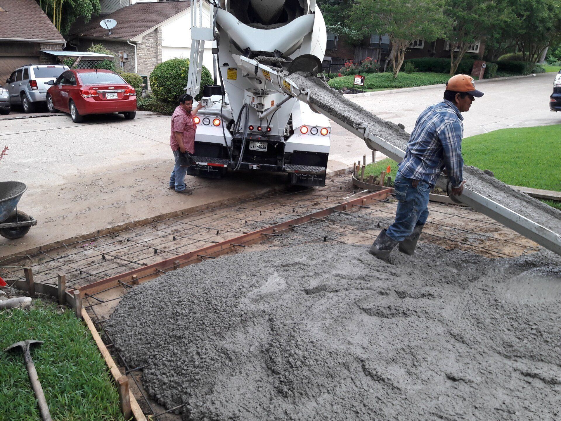 A concrete truck is pouring concrete into a driveway