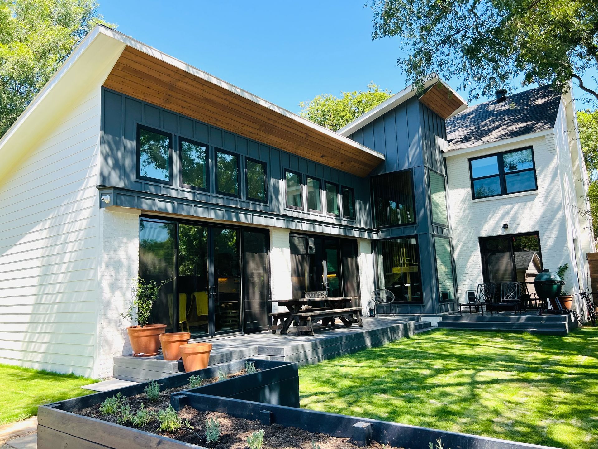 A large house with a lot of windows and a picnic table in the backyard.