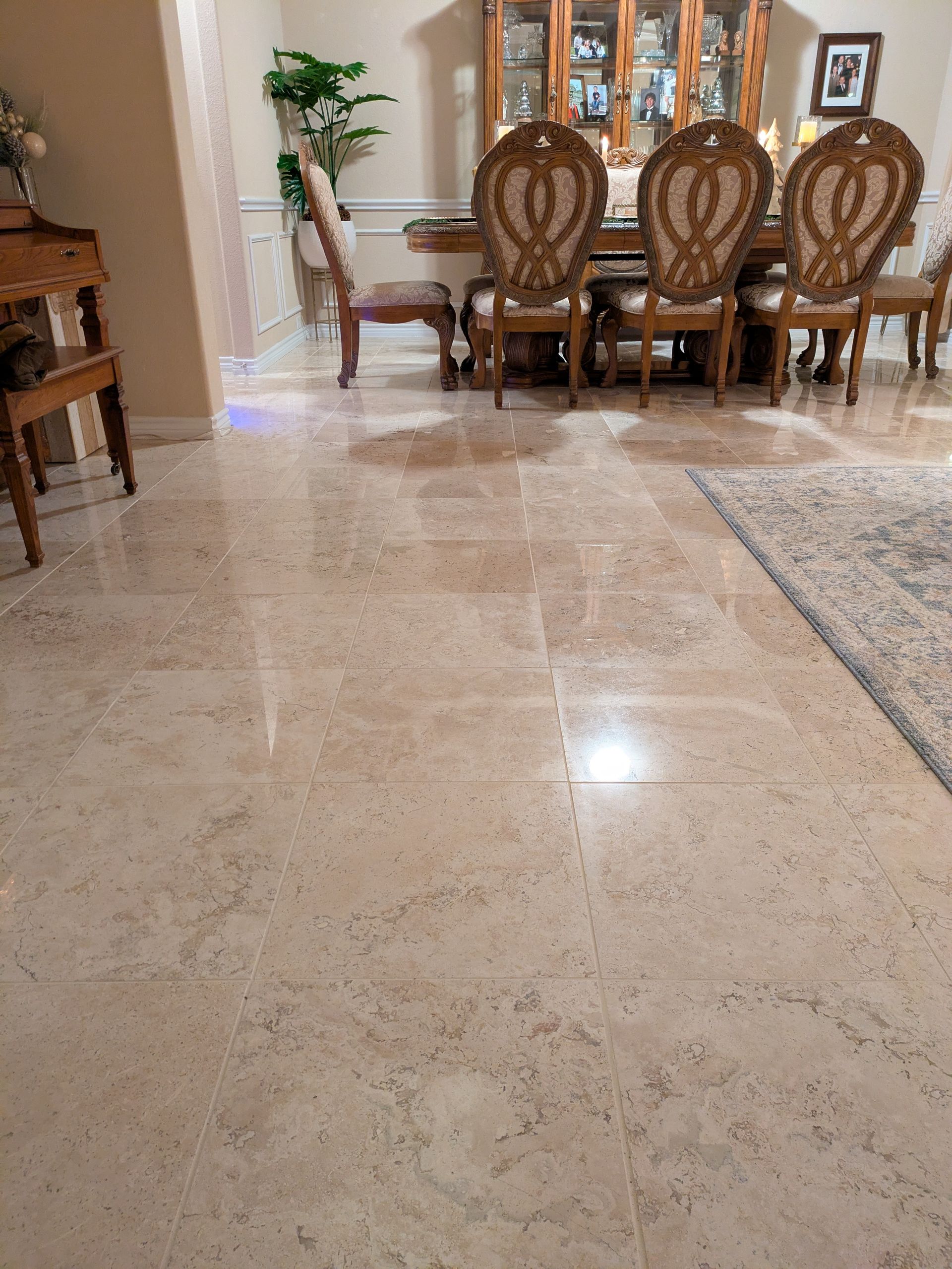 Beige tile flooring in a dining room with a table, chairs, and a cabinet in the background.