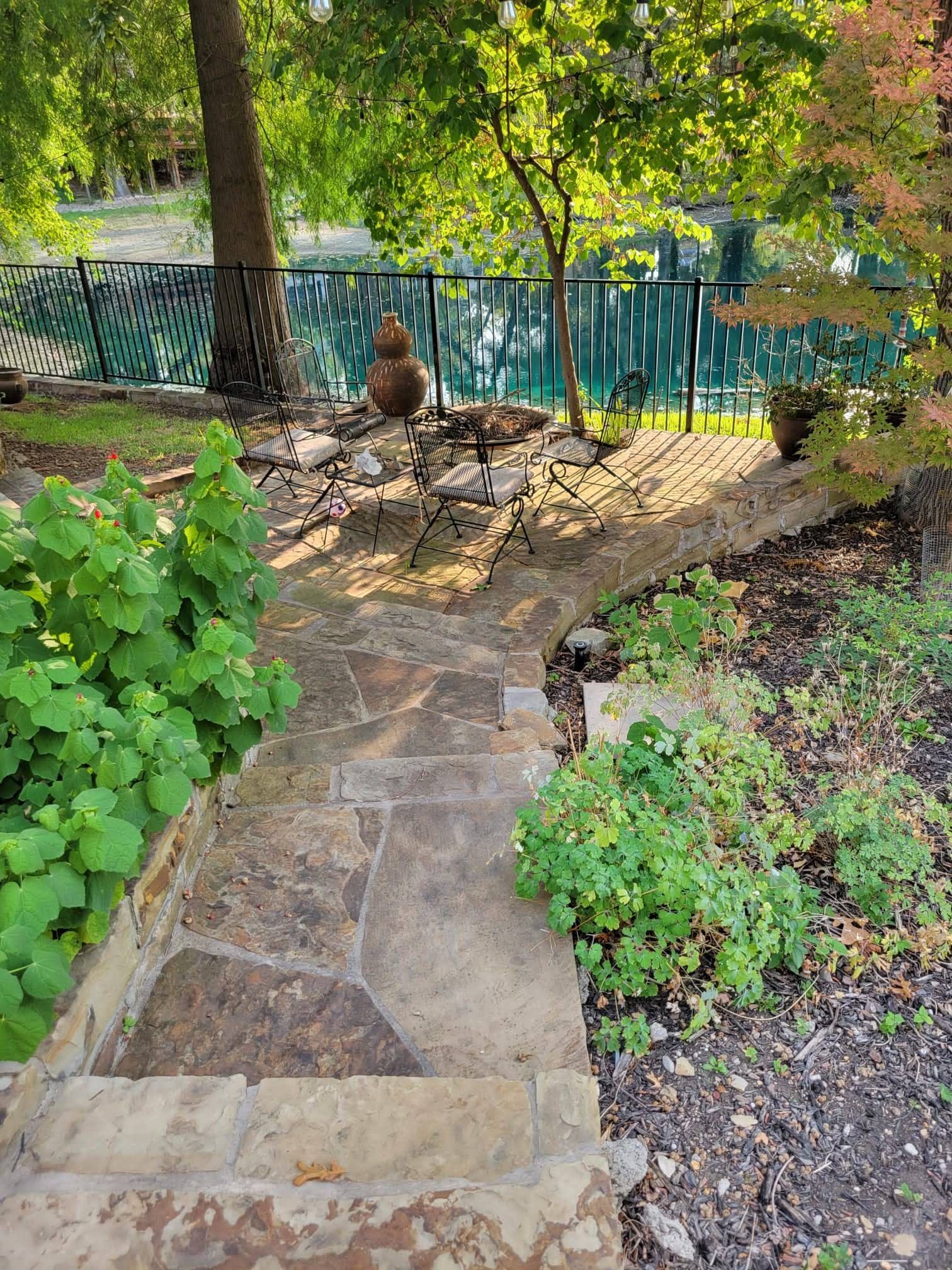 A stone walkway leading to a pool in a backyard.