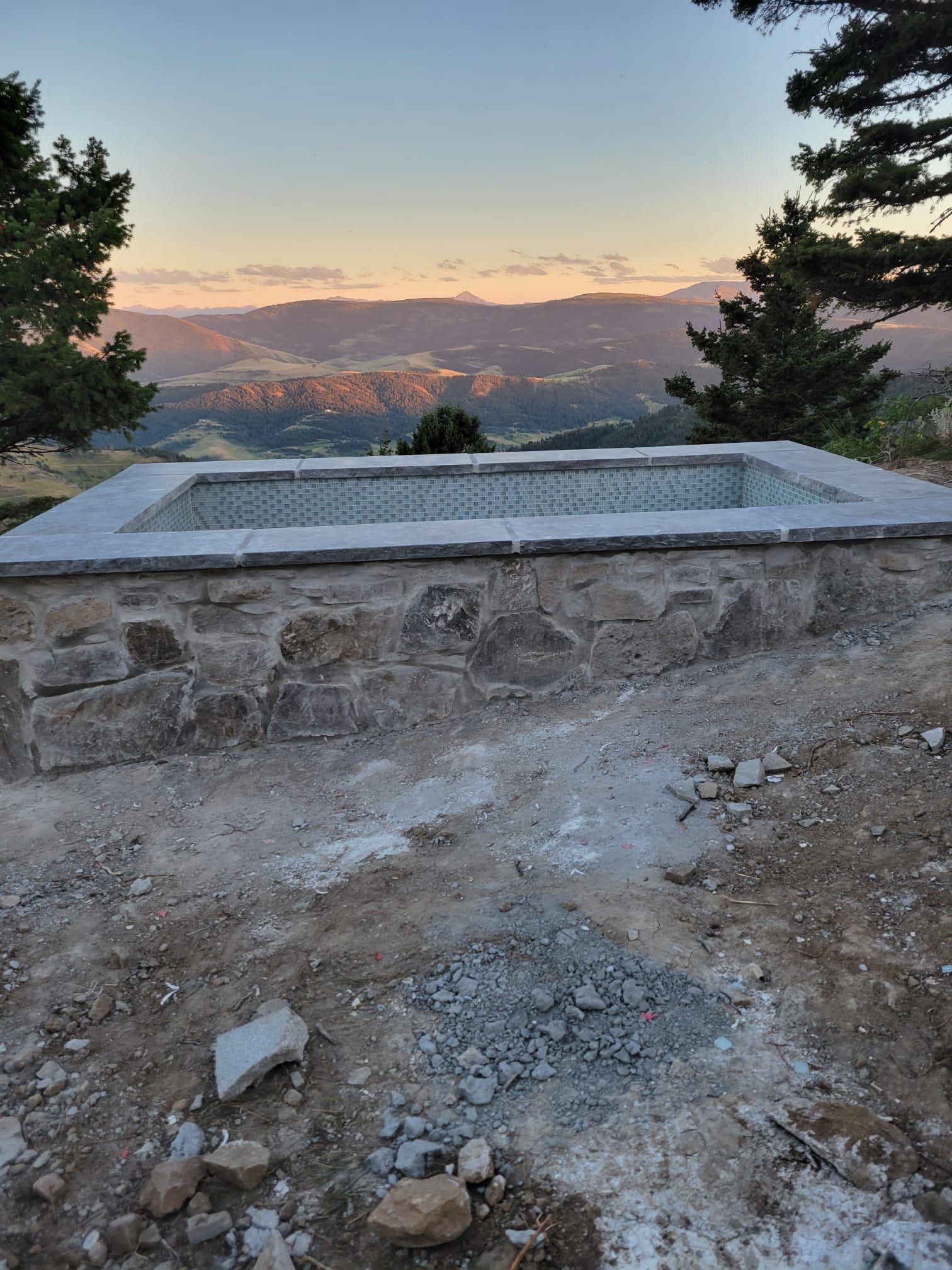 A swimming pool is being built in the middle of a dirt field.