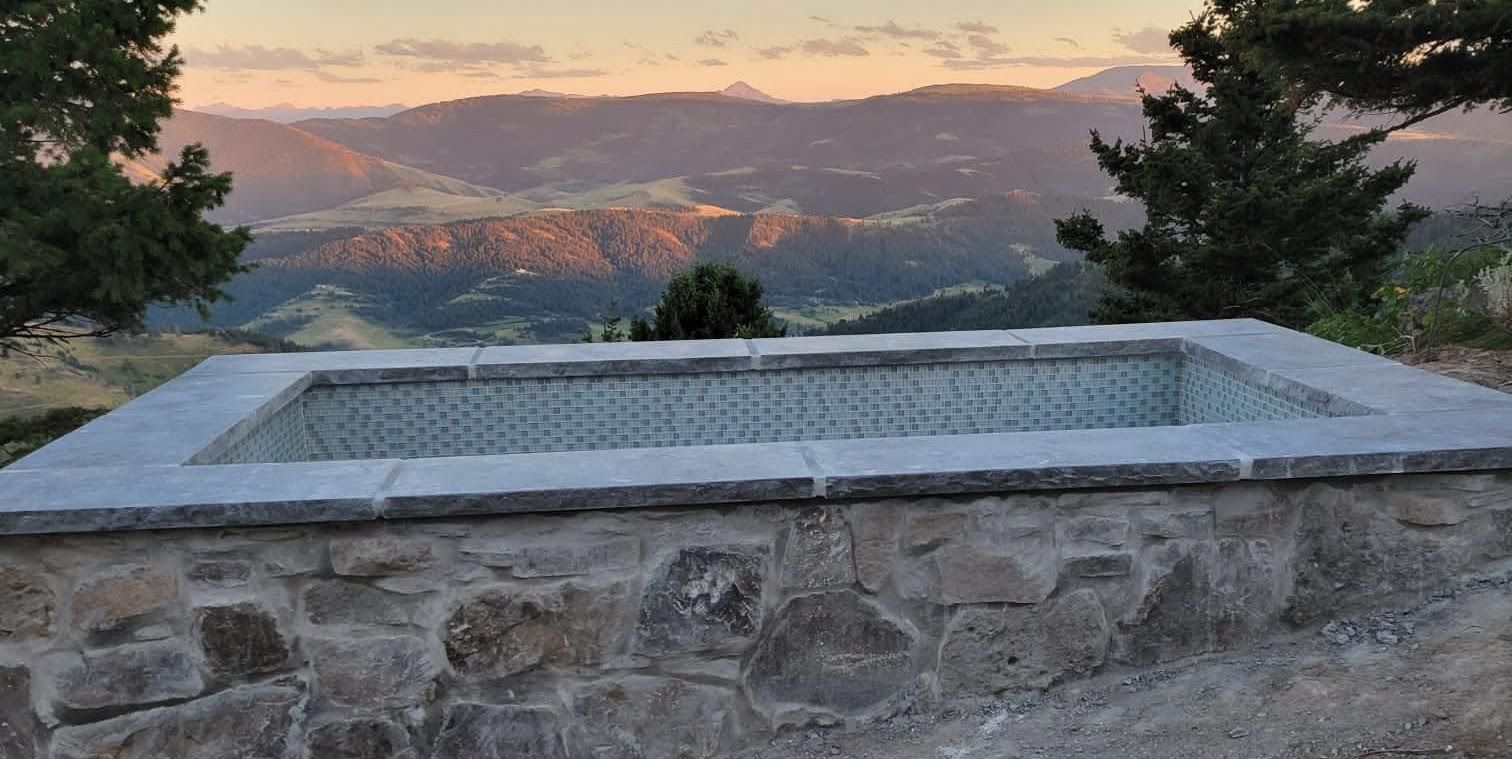 A large stone bathtub with a view of mountains in the background.