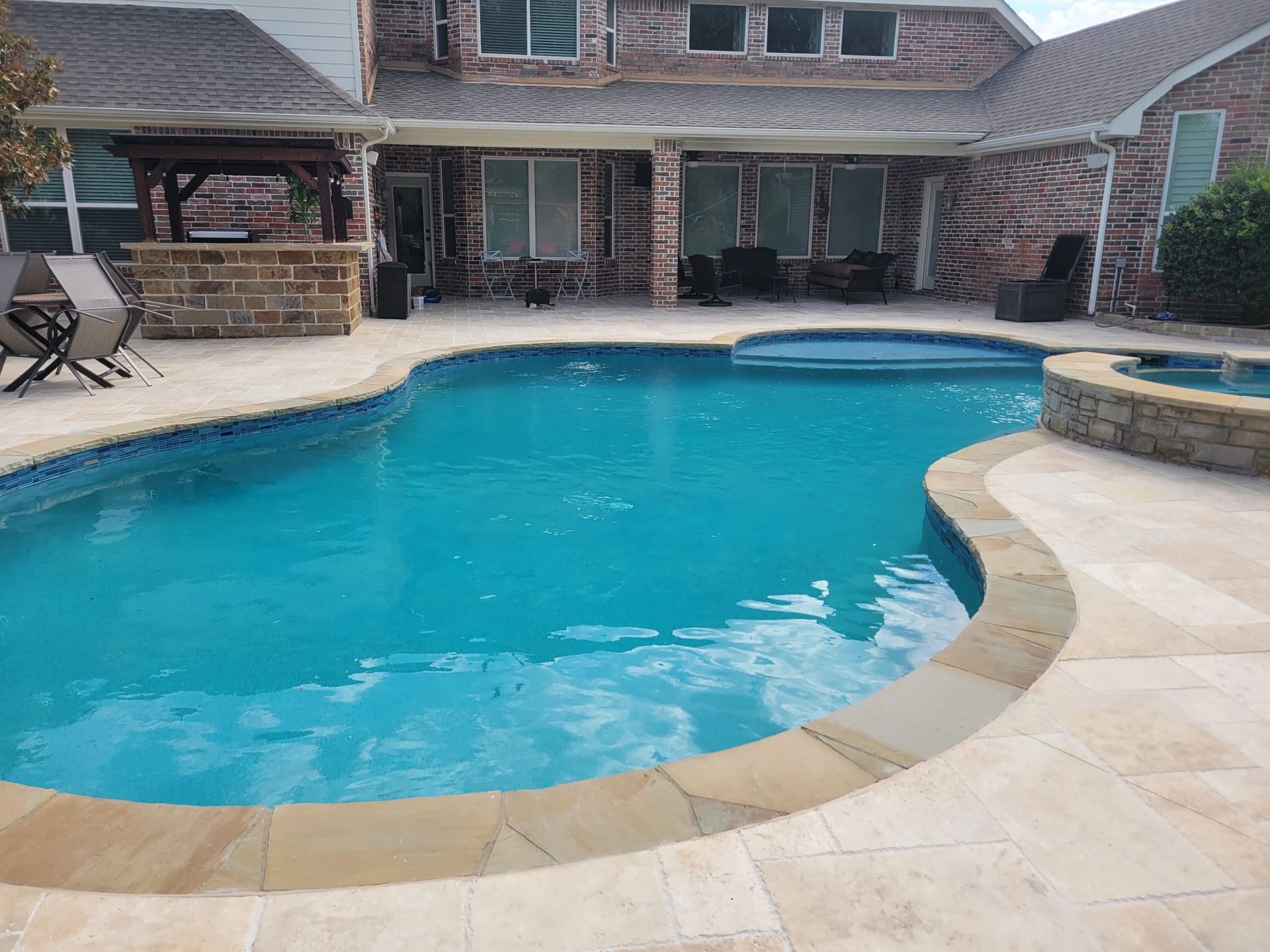 A large swimming pool is in the backyard of a house.