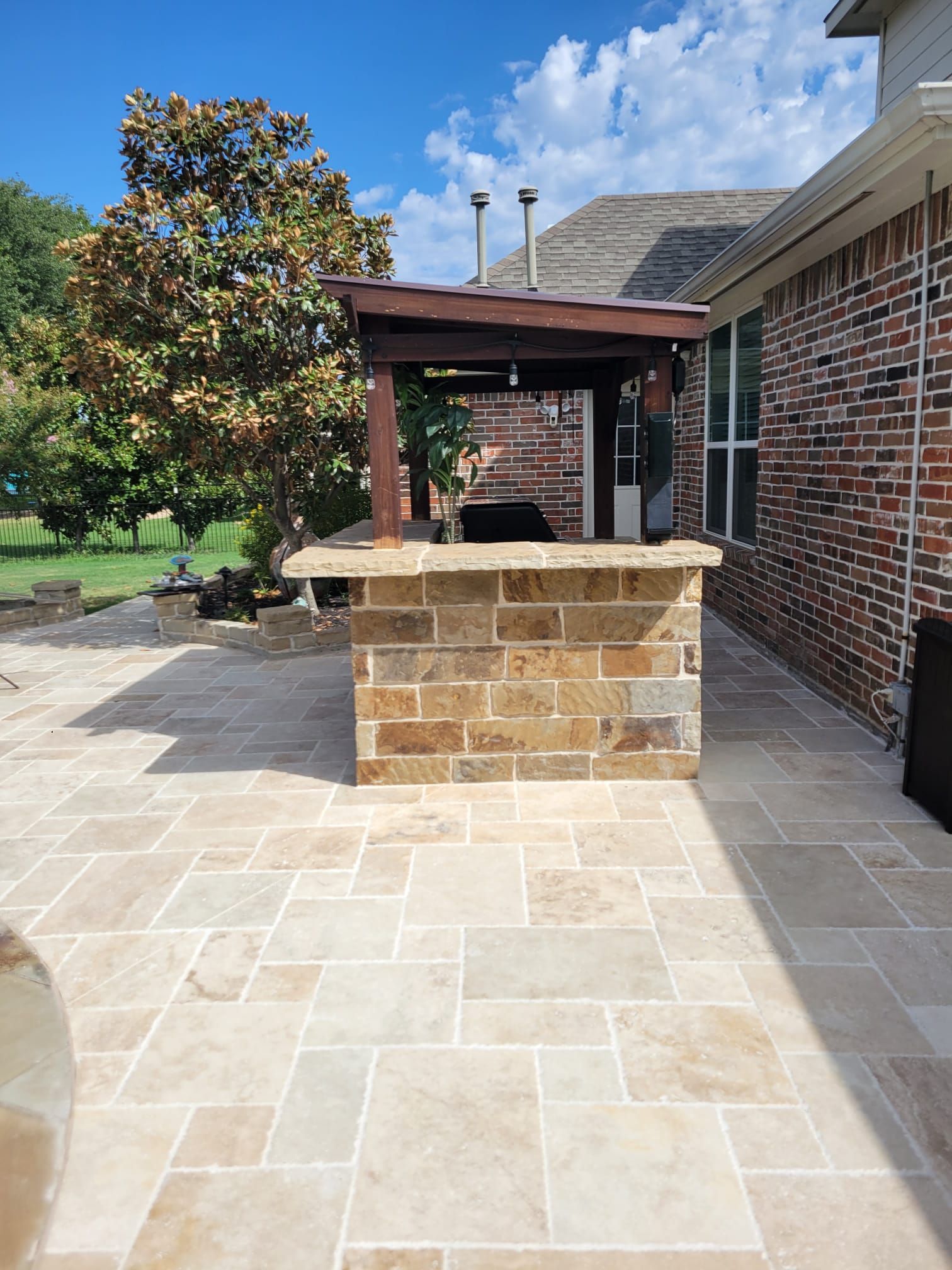 A patio with a brick bar and a brick house in the background.