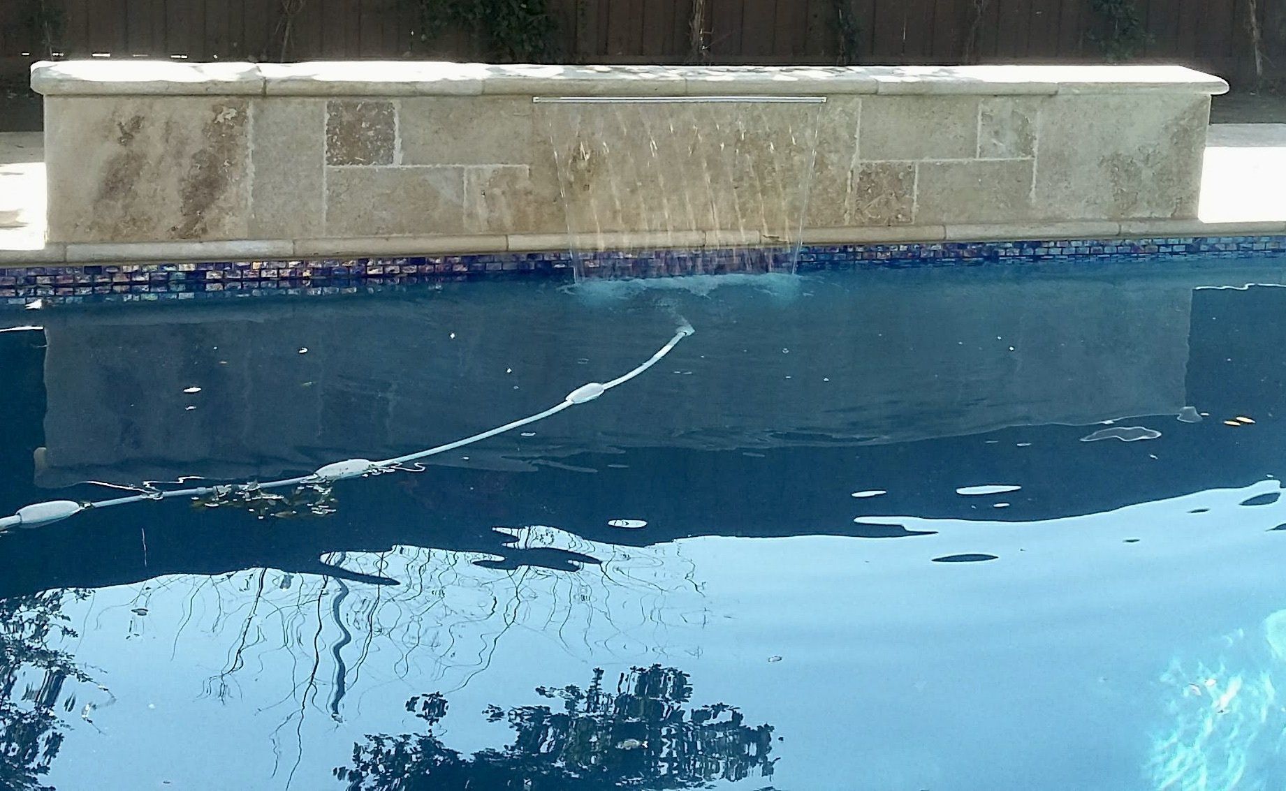 A swimming pool with a stone ledge in the middle