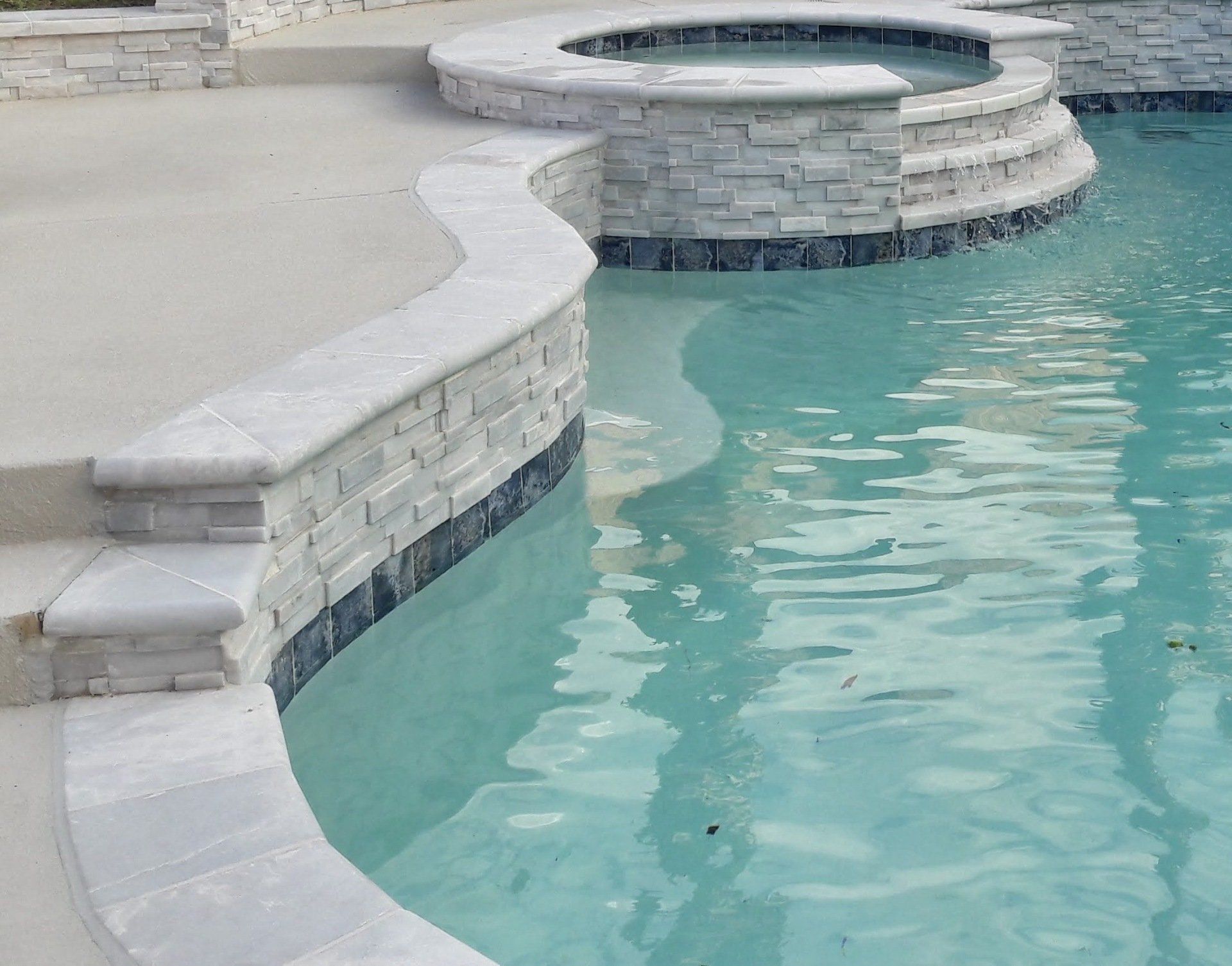 A swimming pool with a hot tub in the middle