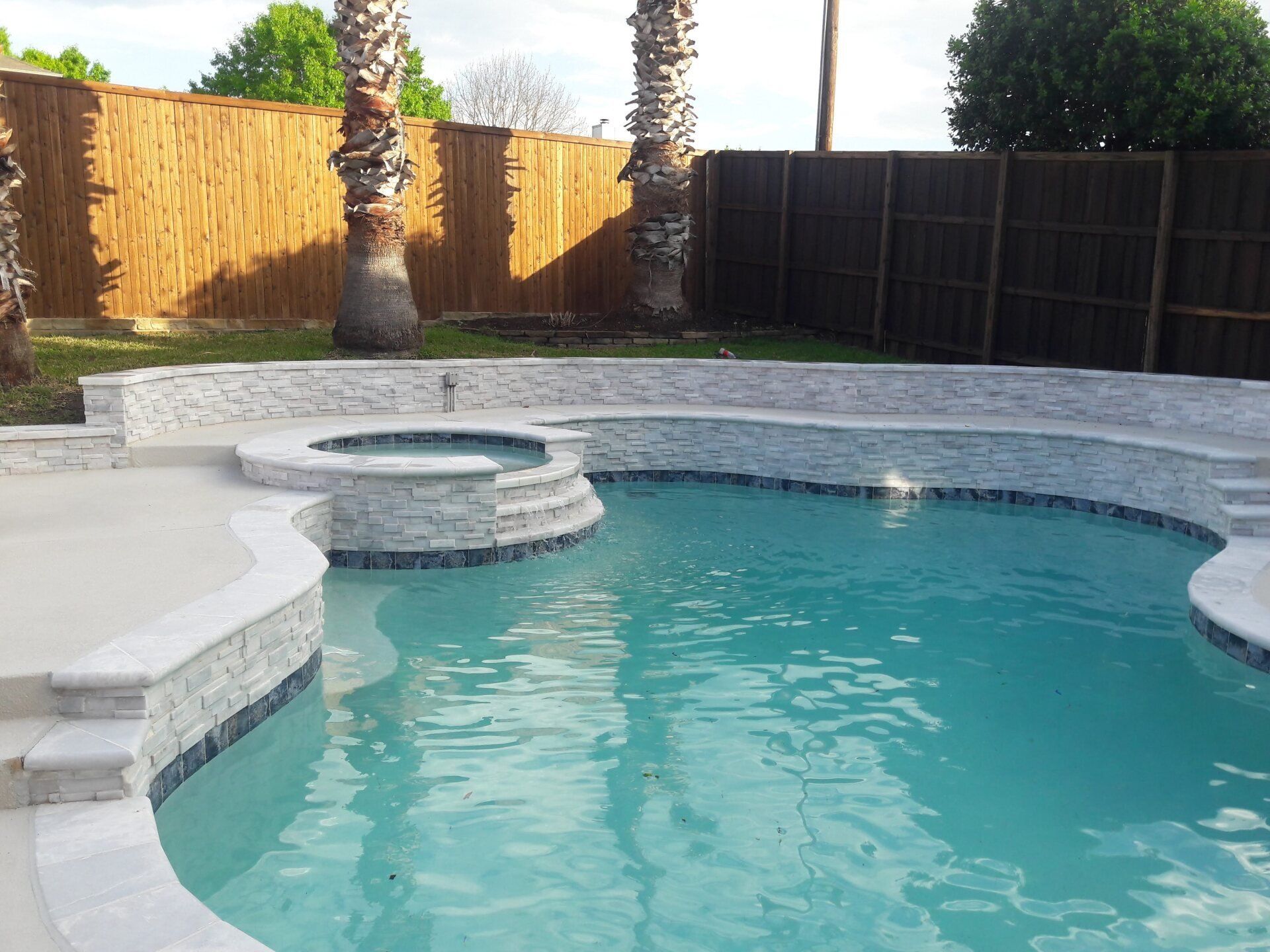 A large swimming pool with a wooden fence in the background