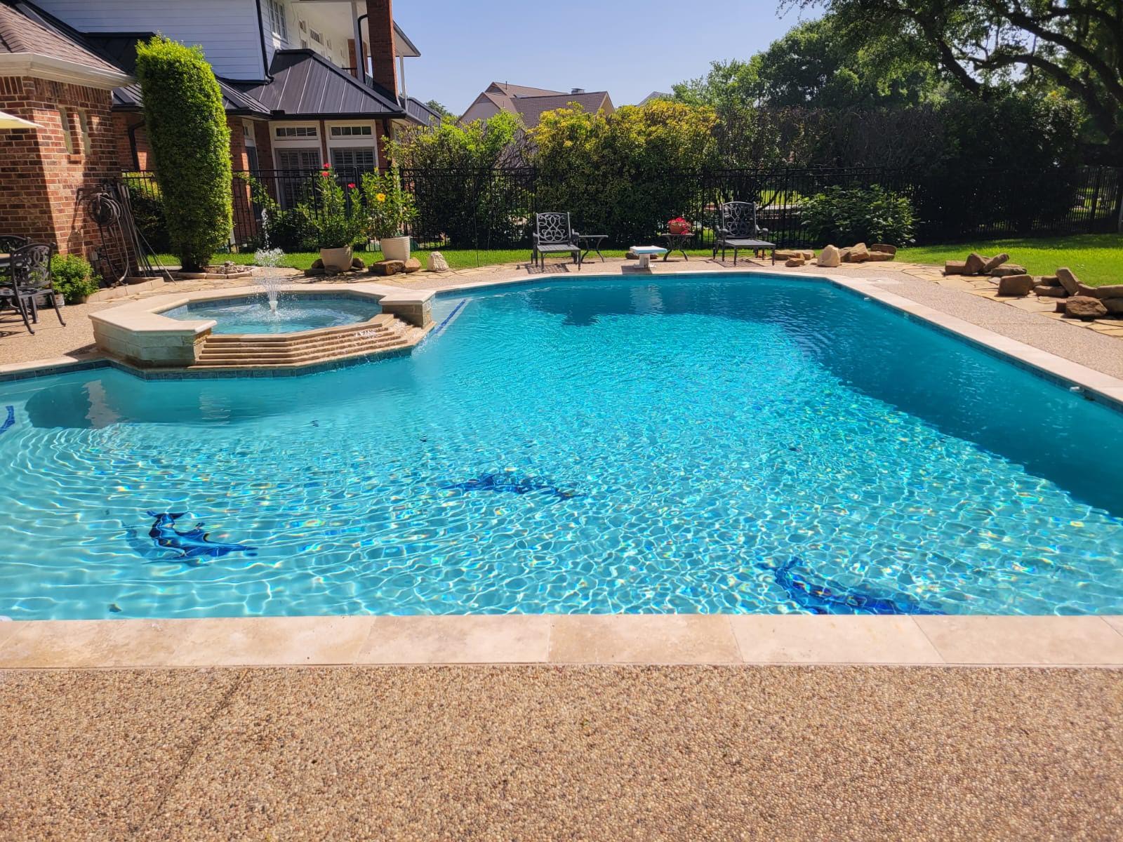 There is a large swimming pool in the backyard of a house.