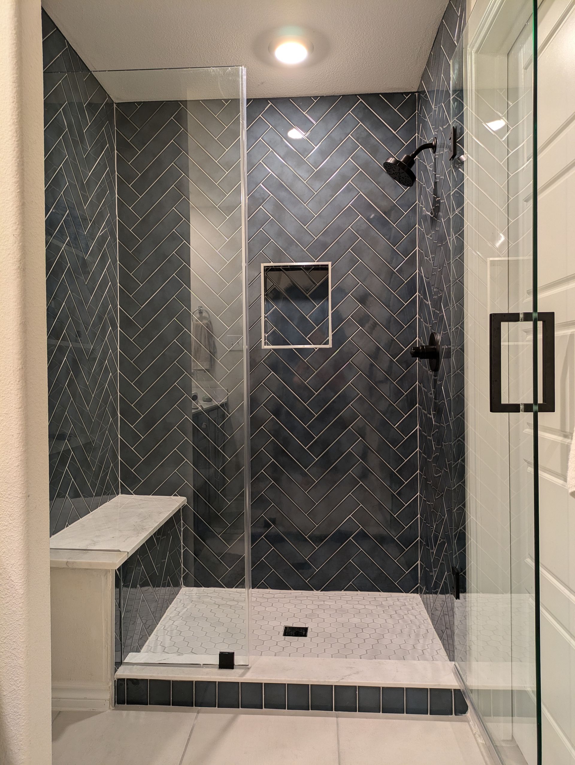 A bathroom with a walk in shower and a bench.