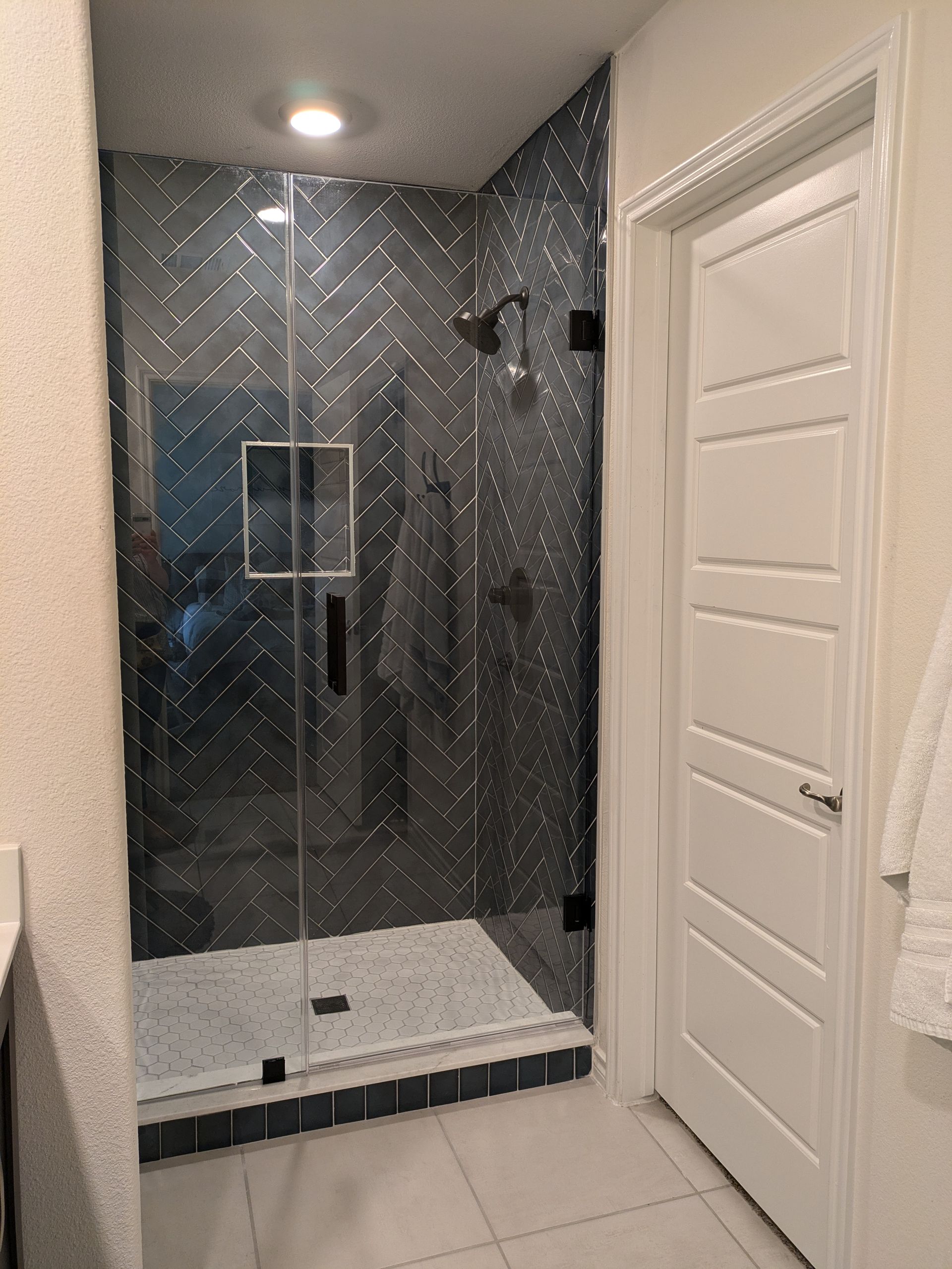 A bathroom with a walk in shower and a white door.