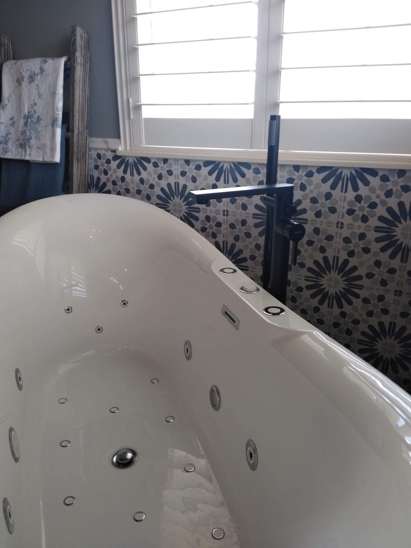A bathtub with jets in it is in a bathroom next to a window.