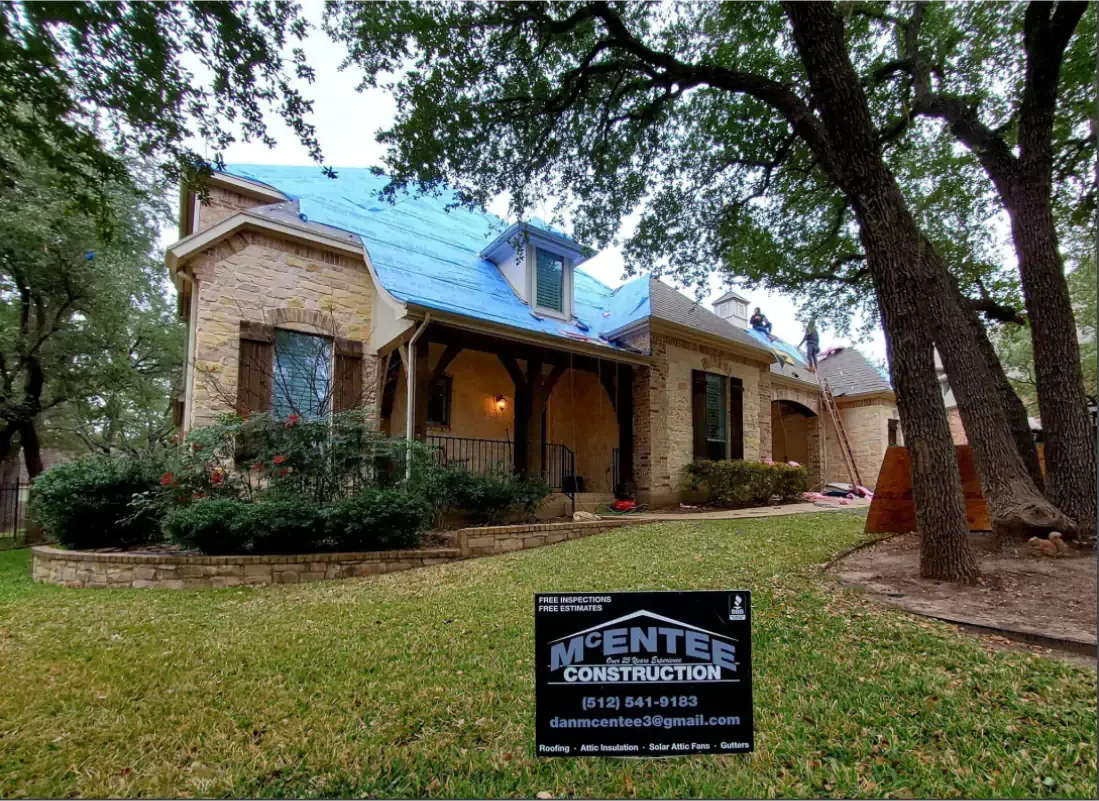 House with blue tarp roof, brick and wood exterior, lawn, sign for Mentes Construction.
