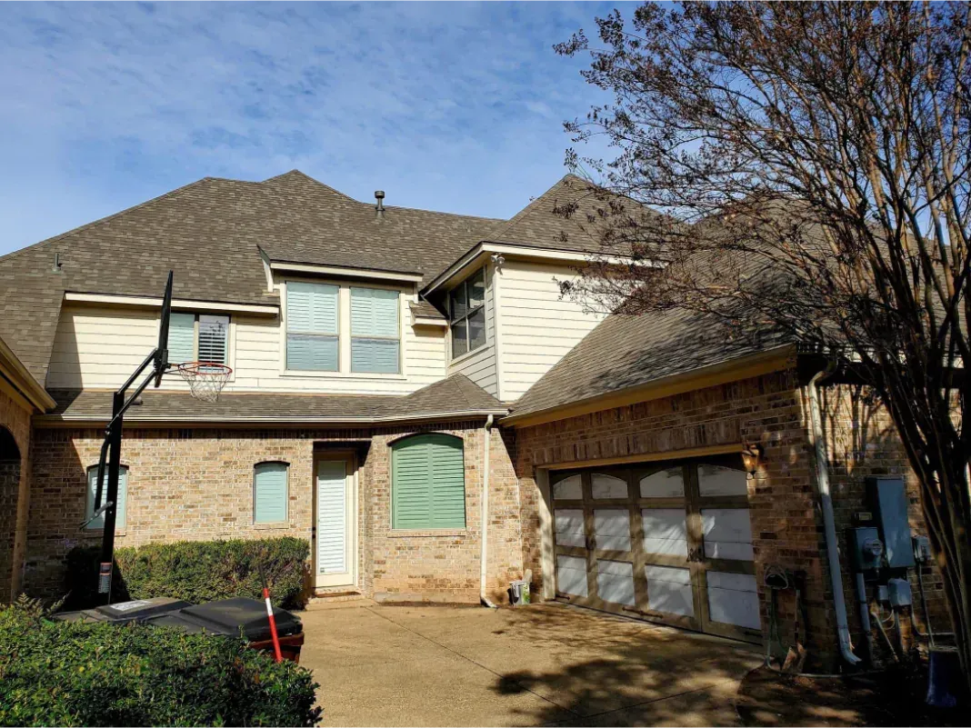 Brick house with brown roof, two-car garage, and blue sky.