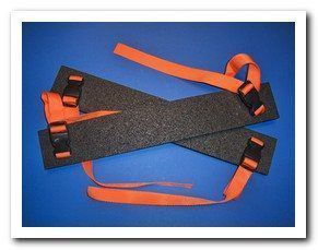 Two black rectangular foam pads with orange straps and buckles, on a blue background.
