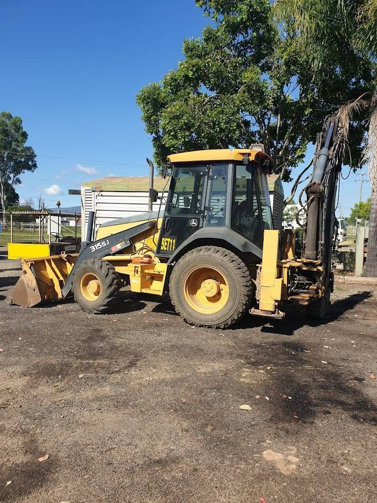 Yellow and Black Backhoe on Dirt, Under a Blue Sky, Near Trees — RCM Diesel & Hydraulic Services in West Rockhampton, QLD