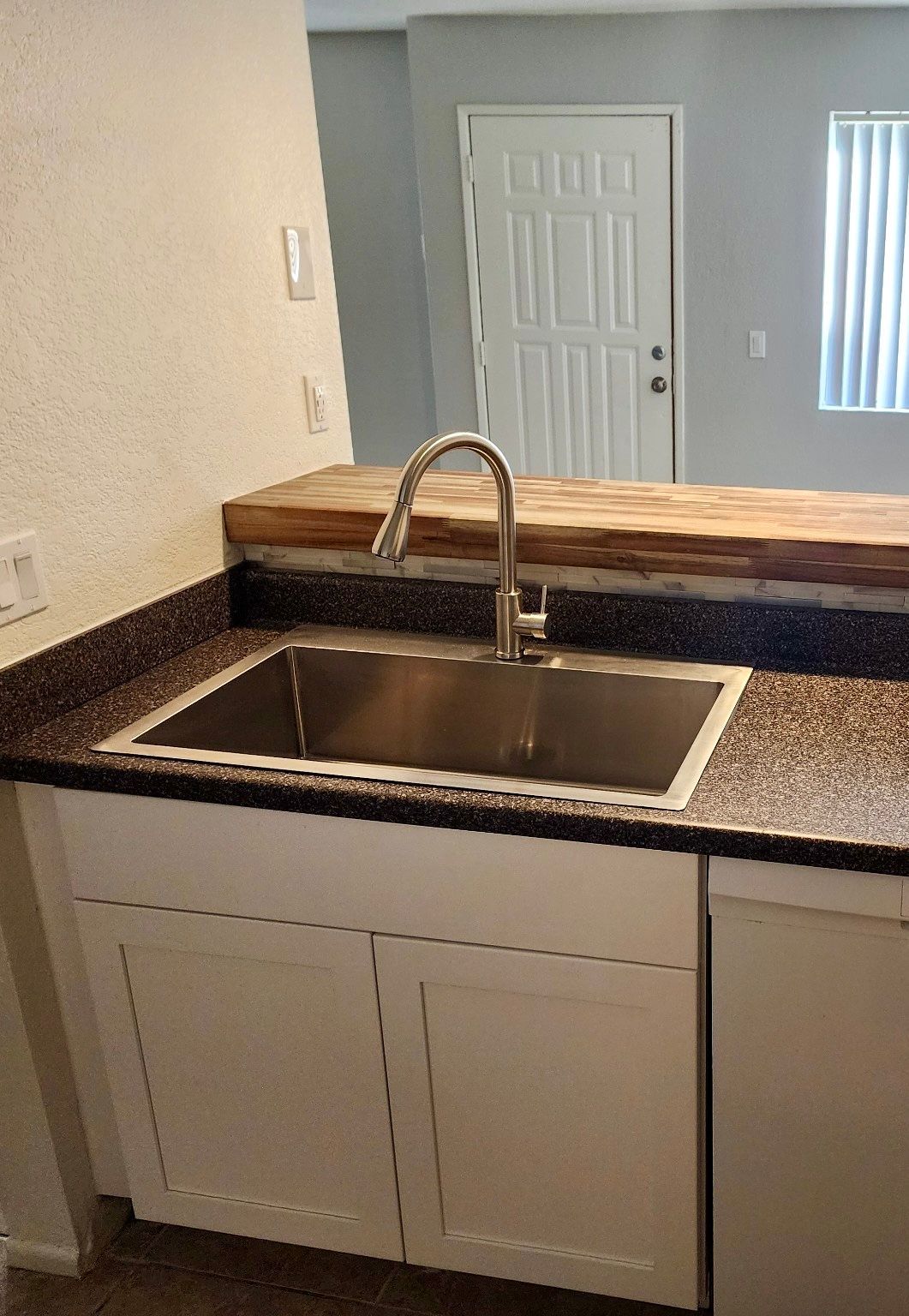 A kitchen with a stainless steel sink and a dishwasher.