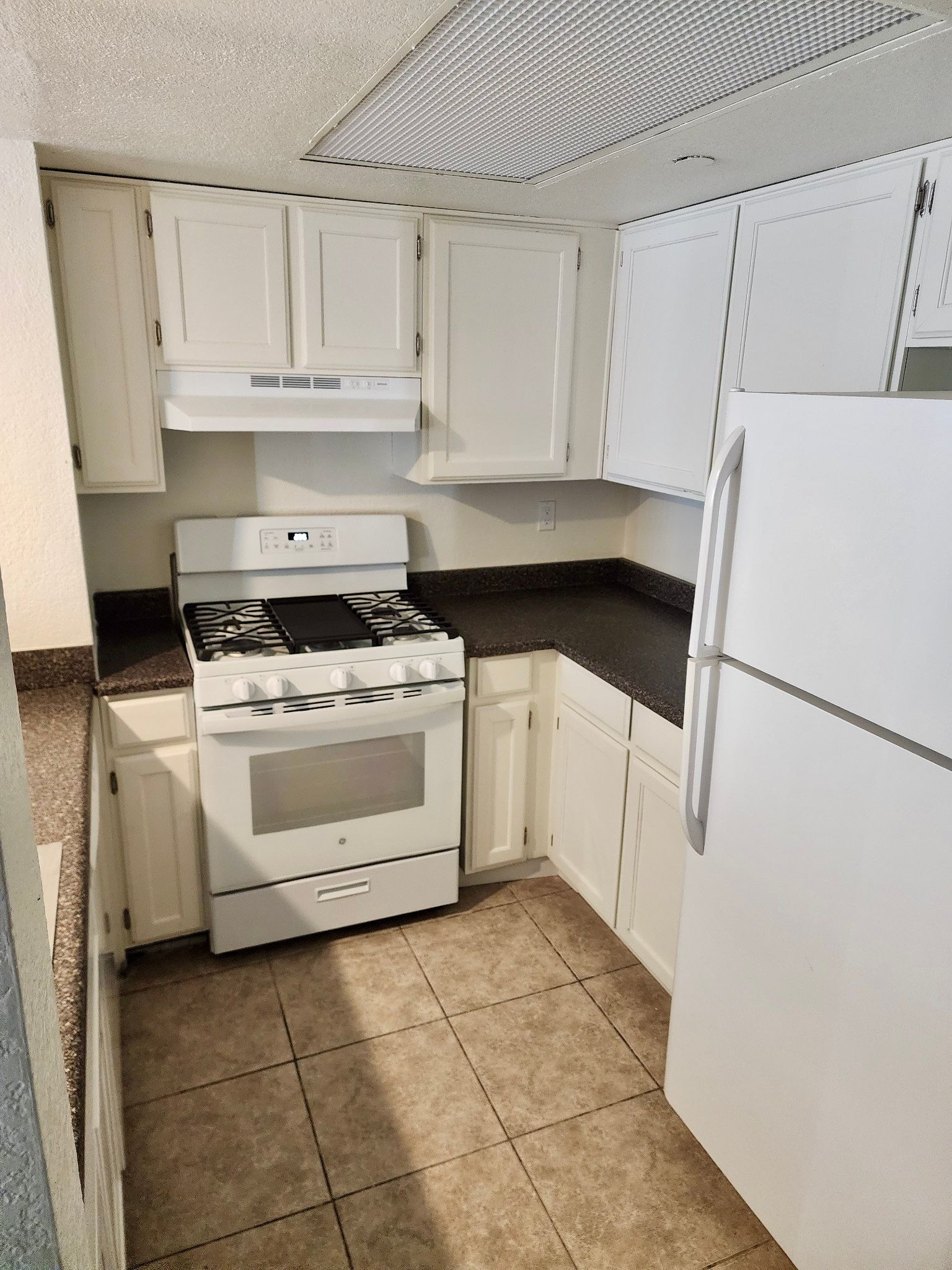A kitchen with a stove , refrigerator , and cabinets.